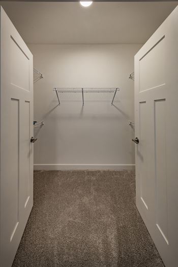 Open french doors reveal a spacious closet with wire shelving.